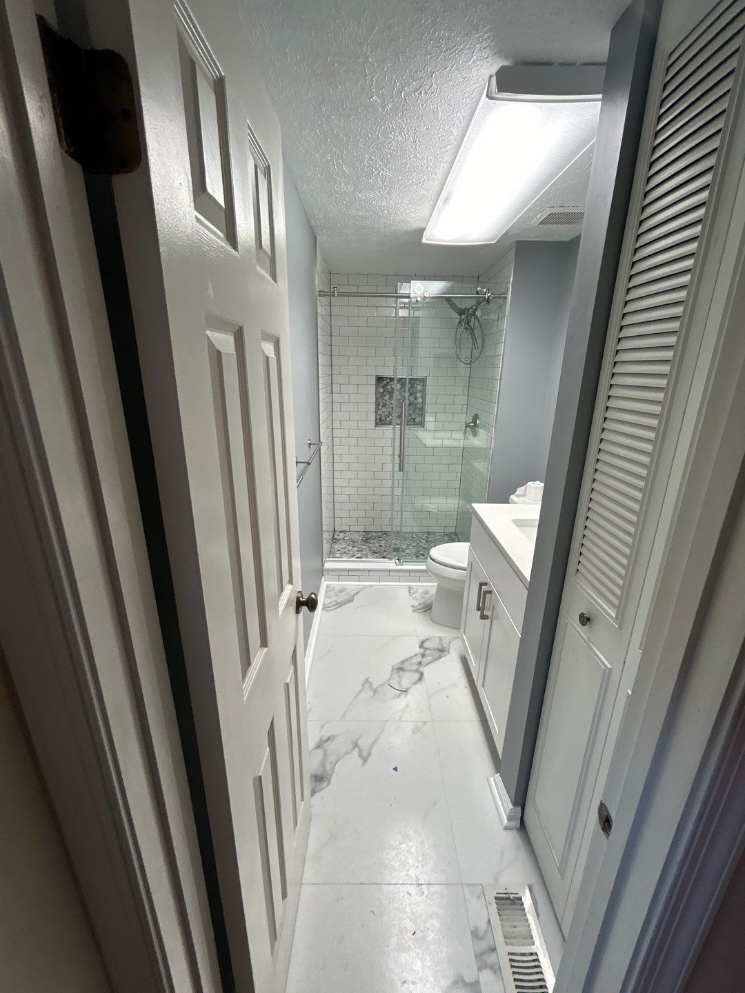 Modern bathroom with glass shower and marble flooring.