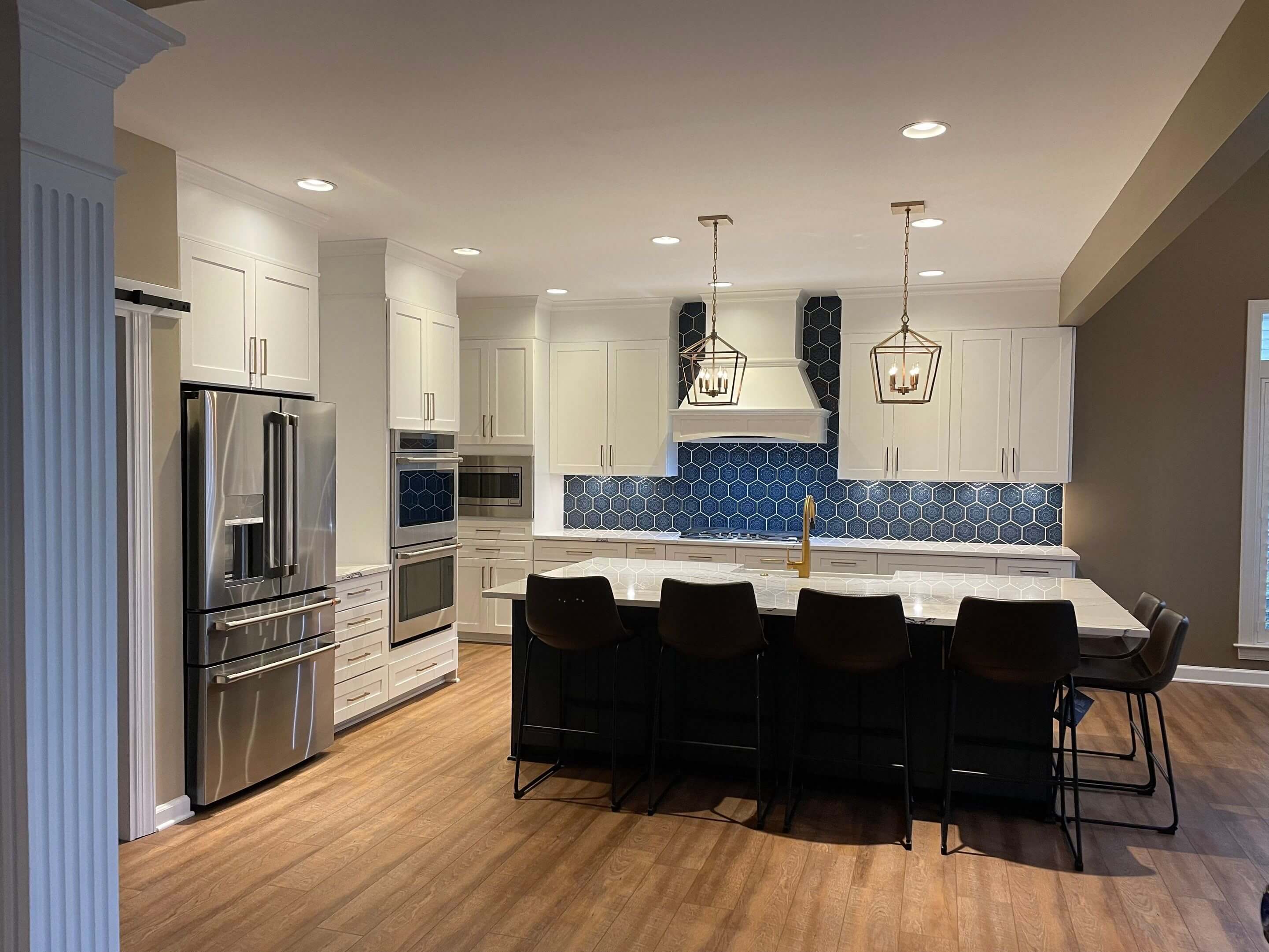 Modern kitchen with white cabinets, blue backsplash, and black bar stools.