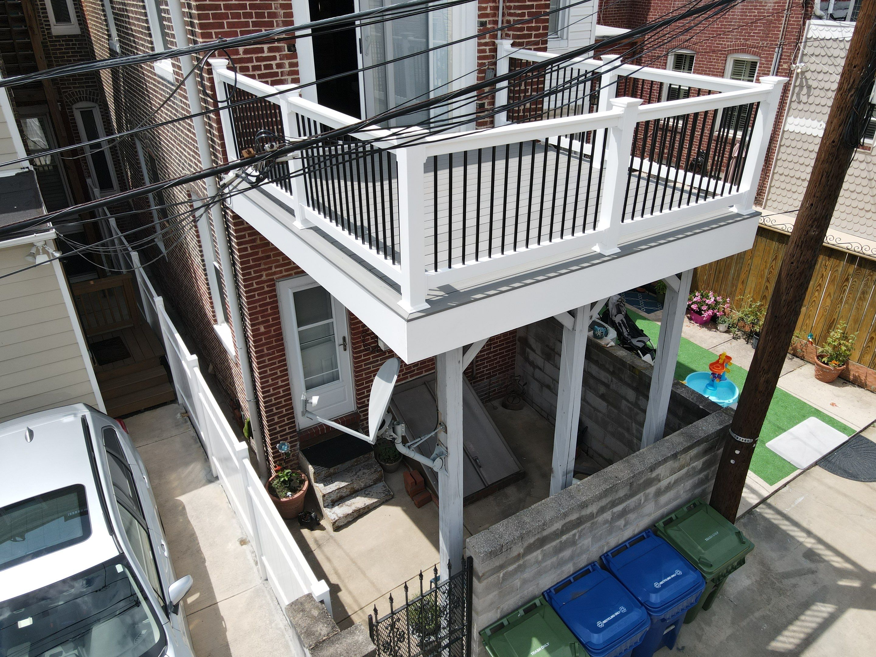 Brick townhouse with white balcony and bins