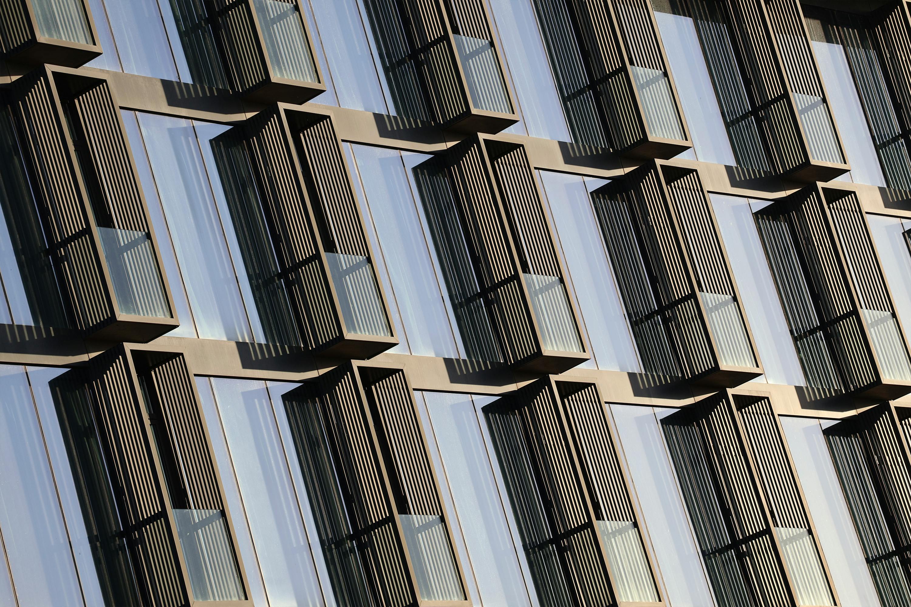 Architectural detail of a modern building facade with glass windows and geometric patterns.