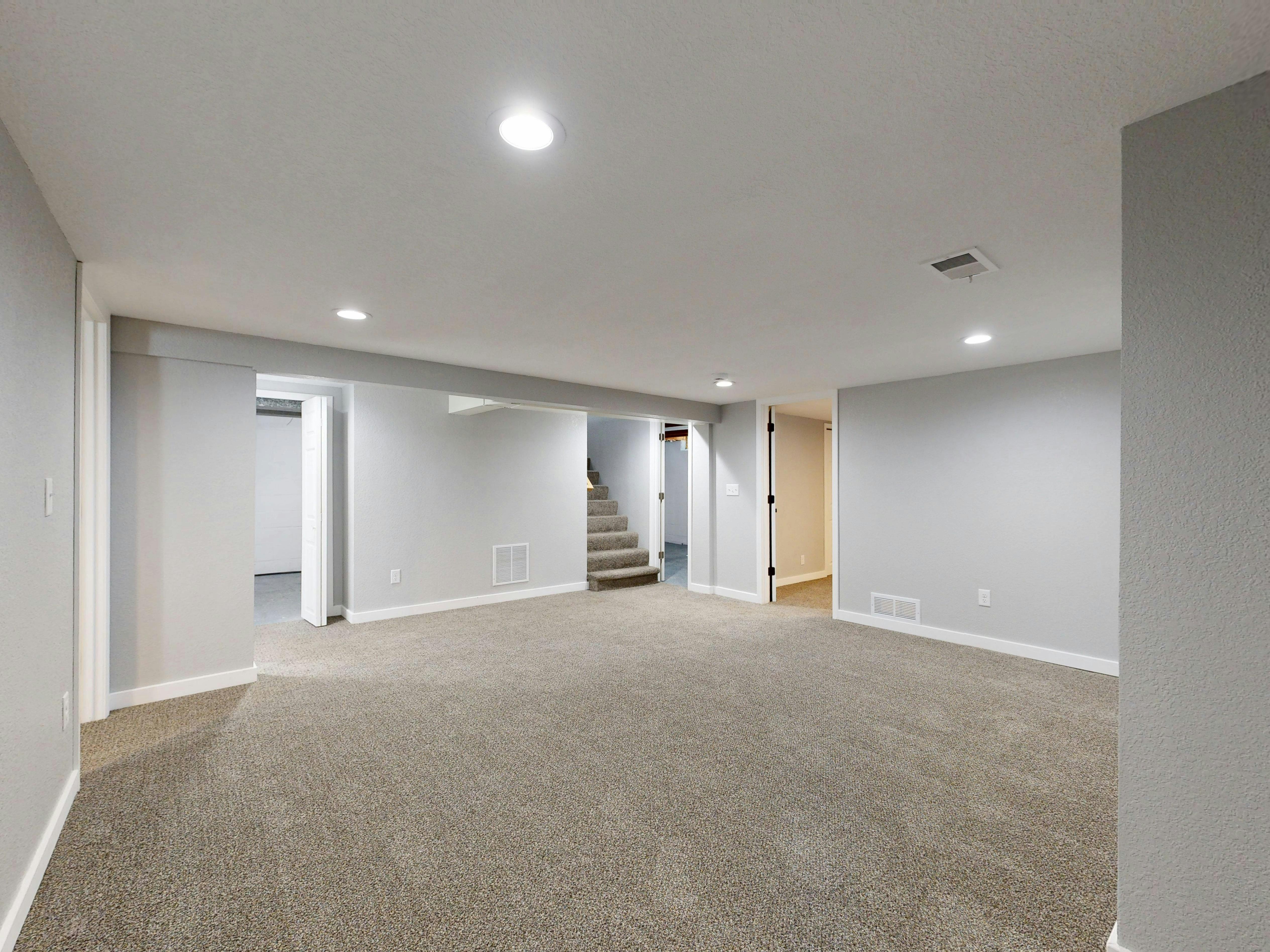 Spacious modern basement with neutral design and carpet flooring, perfect for renovation or real estate listings.
