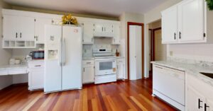 Bright kitchen featuring white cabinets and appliances with hardwood floors.