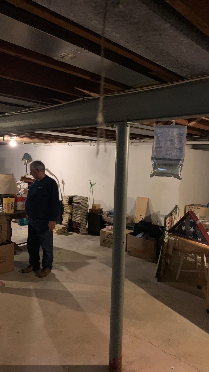Man inspecting cluttered basement with support columns