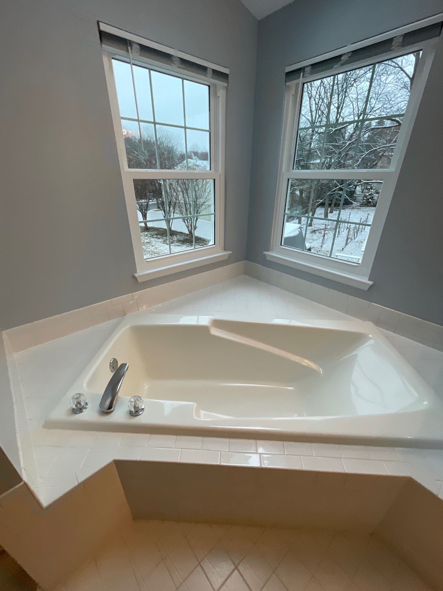 Corner soaking tub with snowy window view